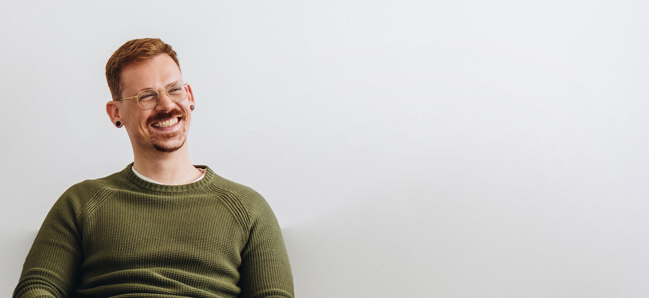 ein Mann sitzt auf einem Stuhl mit gekreuzten Füßen