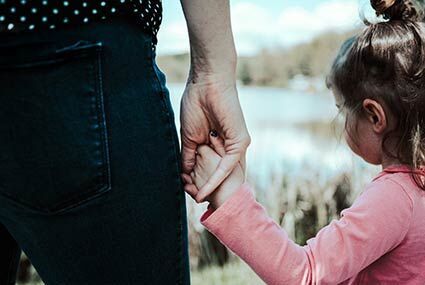 eine Frau, die die Hand eines kleinen Mädchens hält