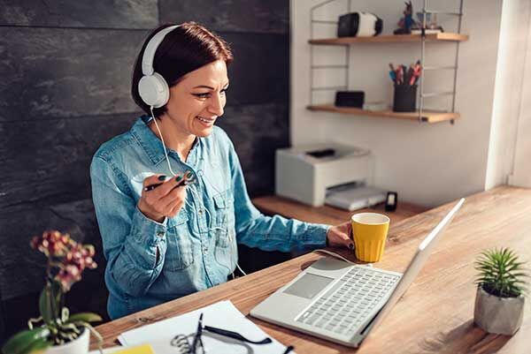 eine Frau sitzt an einem Schreibtisch mit Kopfhörern auf