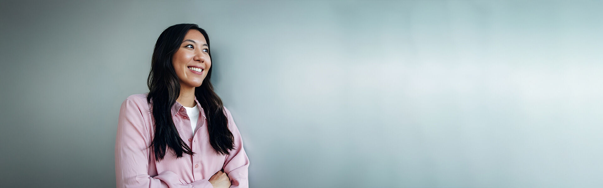 eine Frau in einer rosa Jacke, die gegen eine Wand steht